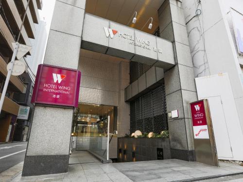 a building with a red sign in front of it at Hotel Wing International Ikebukuro in Tokyo