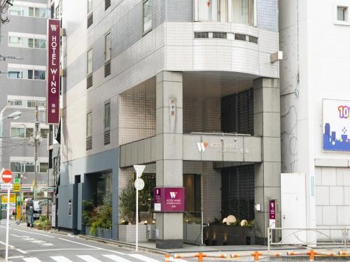 a tall building on a city street with a street at Hotel Wing International Ikebukuro in Tokyo