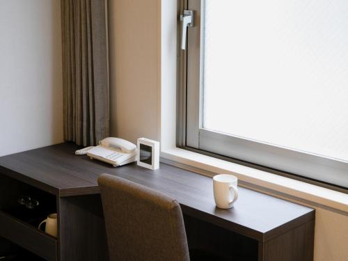 a desk with a phone and a cup on it at Hotel Wing International Ikebukuro in Tokyo