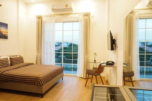a bedroom with a bed and a desk and a window at The Square 101 in Bangkok