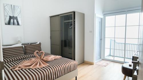 a bedroom with a bed with a dresser and a large window at The Square 101 in Bangkok