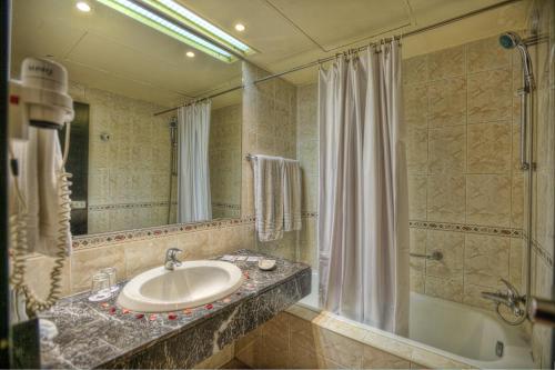 a bathroom with a sink and a shower and a tub at Hôtel Marrakech Le Semiramis in Marrakech