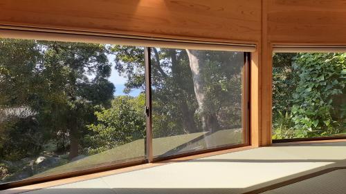 two windows in a room with a view of trees at Cottage Views in Yakushima