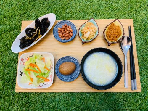 ein hölzernes Tablett mit Schalen mit Lebensmitteln und Teller mit Lebensmitteln in der Unterkunft 日月潭沅居民宿 YUAN JU BOUTIQUE Hotel in Yuchi