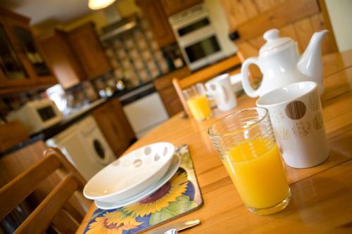 a table with a cup of orange juice and a glass of orange juicektop at Windrush Cottage, Seven Springs Cottages in Cheltenham