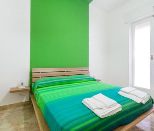 Un dormitorio verde con una cama con toallas. en Porta Nuova en Marsala