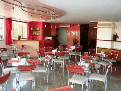 um restaurante com mesas e cadeiras e paredes vermelhas em Hotel Rosa Mar em Macaé