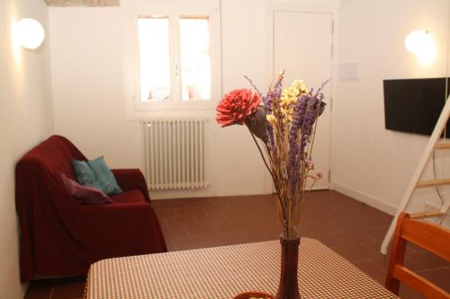 a vase with flowers on a table in a living room at Cal Riba in Llacuna
