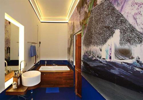 baño con bañera y una gran pintura en la pared en Tanjore Hi Hotel, en Thanjāvūr