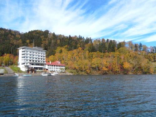 a large building on the shore of a lake at Shikaribetsu Kohan Onsen Hotel Fusui in Shikaoi