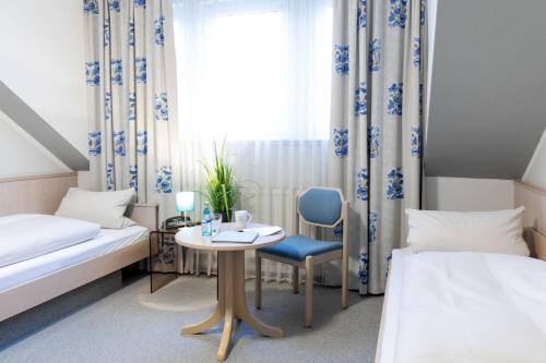 een kamer met 2 bedden, een tafel en een raam bij Hotel Hamm in Weiterstadt