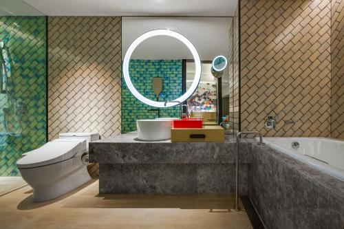 ein Badezimmer mit einem Waschbecken, einem WC und einem Spiegel in der Unterkunft Hotel Indigo Taipei North, an IHG Hotel in Taipeh