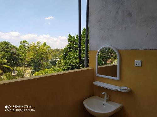 a bathroom with a sink and a mirror and a window at Nature Home in Mirissa