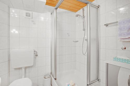 a white bathroom with a shower and a toilet at Ferienwohnung König im Erdgeschoss in Berchtesgaden