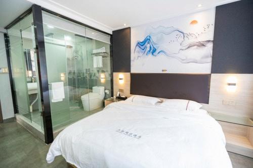 a bedroom with a large white bed and a glass shower at  Shenzhen Hualian Boutique Hotel in Shenzhen