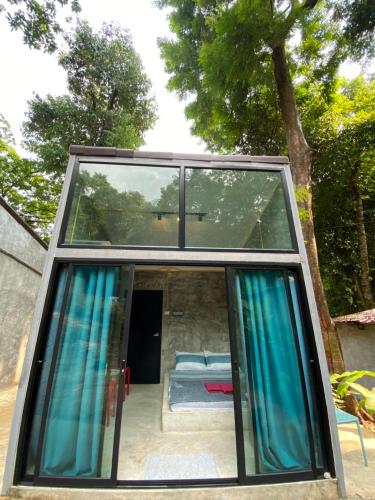 a glass house with blue curtains and a bedroom at BeachBox@Koh Сhang in Ko Chang