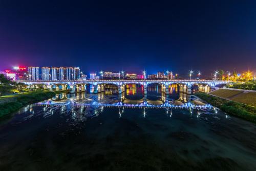a bridge over a river with a city at night at Sky Gate Guesthouse-English Speaking Hostess, Family friendly,2-minute walk to Entrance of Tianmen Mount ,Free pick up service,Book attraction tickets, Free Laundry,Private Tour in Zhangjiajie