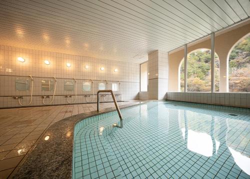 une grande salle de bains avec une piscine et des toilettes. dans l'établissement The Gran Resort Kinosaki, à Toyooka