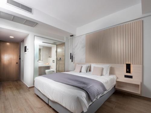 sypialnia z dużym białym łóżkiem i łazienką w obiekcie Athena Hotel w mieście Rodos