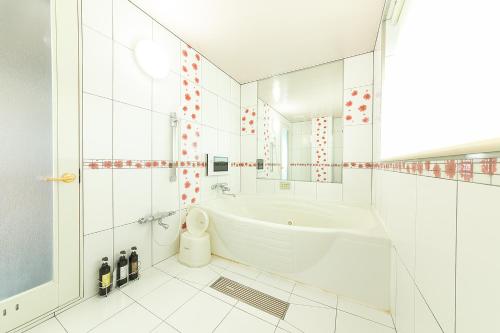 和歌山市にあるホテル　ティーオーの白いバスルーム(バスタブ、鏡付)