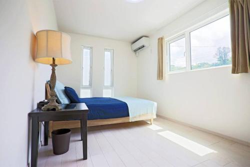 a bedroom with a bed and a lamp on a table at Irie House Motobu in Motobu