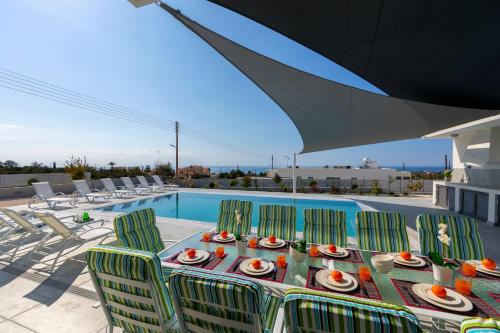 a table with plates of food on it next to a pool at Villa Andromeda, Sea Caves in Peyia