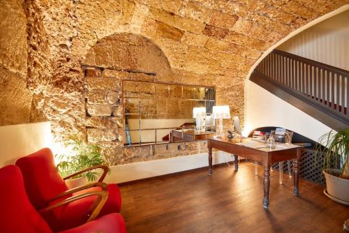 a living room with a table and a stone wall at L' Hôtellerie Easy Suites in Palermo