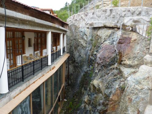 a view from the balcony of a building next to a rock wall at Mountain Rose Hotel & Restaurant in Pedoulas