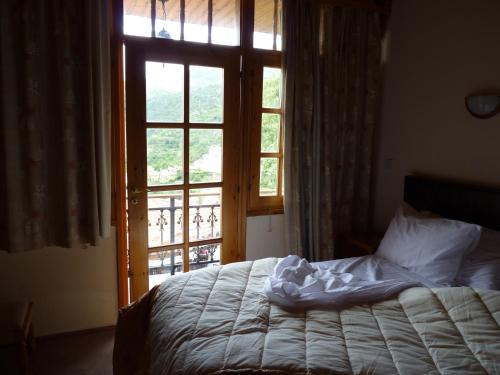 
a bed sitting in front of a window next to a window at Mountain Rose Garden Hotel & Restaurant in Pedoulas
