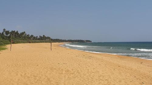 a beach with a volleyball net in the sand at Bandulas Beach House in Hikkaduwa