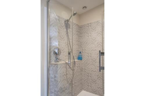 une douche avec une porte vitrée dans une salle de bain dans l'établissement Les Suites de Catherine, la Si Calme, à Nancy