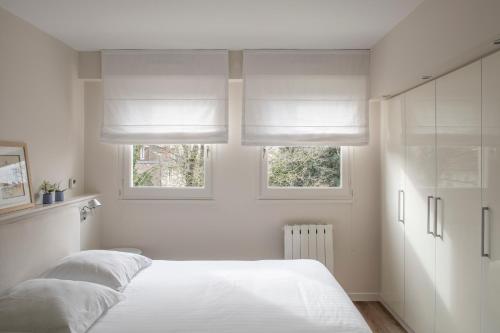ナンシーにあるLes Suites de Catherine, la Si Calmeの白いベッドルーム(ベッド2台、窓2つ付)が備わります。