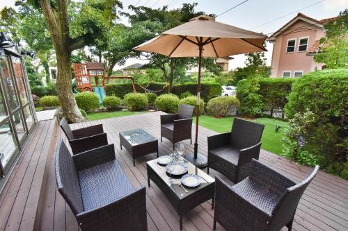a patio with chairs and a table with an umbrella at KandoStay 伊豆高原パークガーデン in Ito