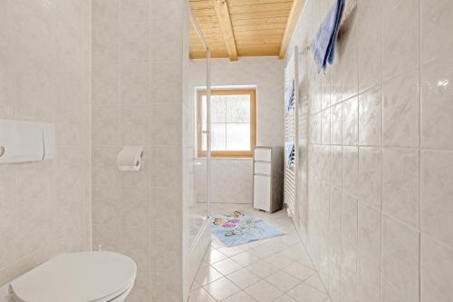 a white bathroom with a toilet and a window at Ferienwohnung König im Obergeschoss in Berchtesgaden