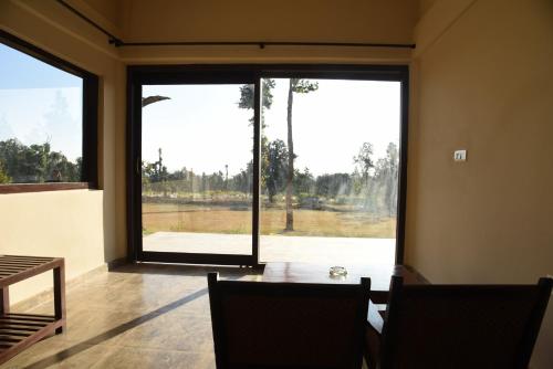 a dining room with large windows and a table and chairs at Hideaway By Aahma in Rāmnagar