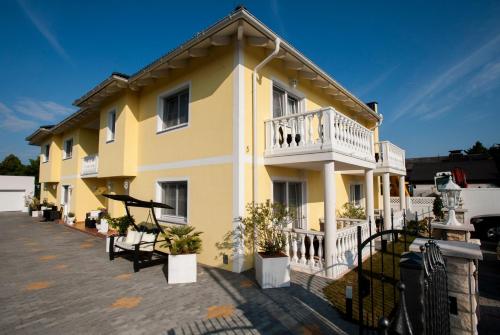 a yellow house with a balcony on a parking lot at Villa Katharina in Rust