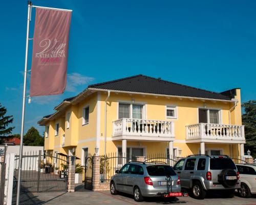 a yellow building with cars parked in front of it at Villa Katharina in Rust
