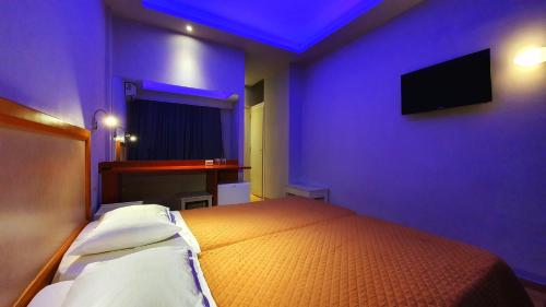 イプソスにあるOnar Corfu Aparts & Studiosの紫の壁にテレビとベッドが備わるベッドルーム1室が備わります。