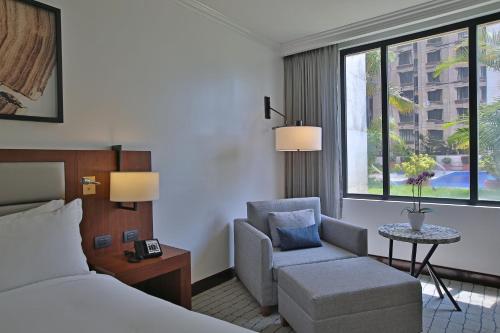 a hotel room with a bed and a chair and a window at Intercontinental Real Guatemala by IHG in Guatemala