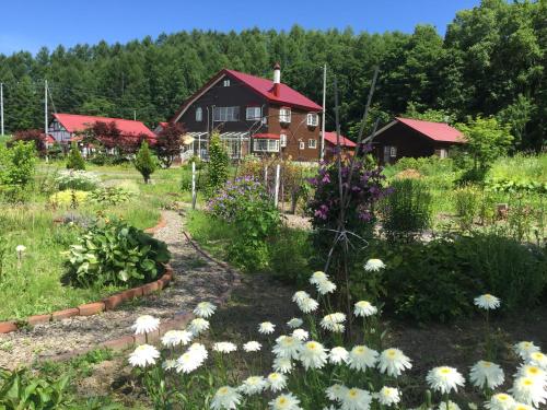a garden with flowers in front of a house at Natsumi no Sato in Biei