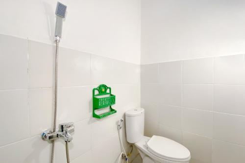 a bathroom with a toilet and a green sign on the wall at Super OYO Capital O 3092 Falah Residence Syariah in Padang