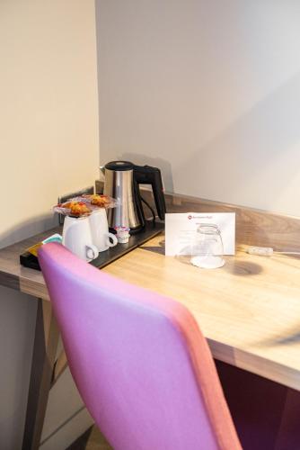 a purple chair in front of a table with a coffee maker at Best Western Plus Paris Velizy in Vélizy-Villacoublay