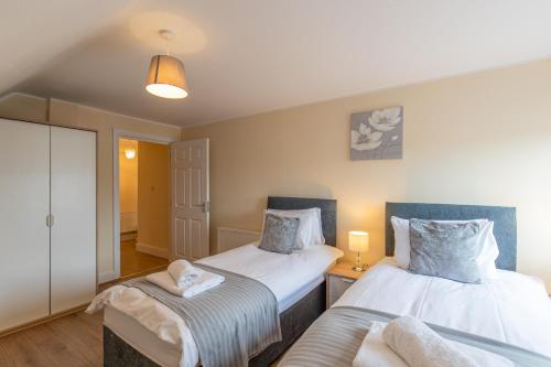 a bedroom with two beds and a table with two lamps at 2 Bedroom Penthouse, Clockhouse, Hoddessdon in Hoddesdon