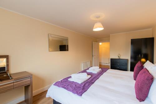 a bedroom with a large white bed with purple sheets at 2 Bedroom Penthouse, Clockhouse, Hoddessdon in Hoddesdon