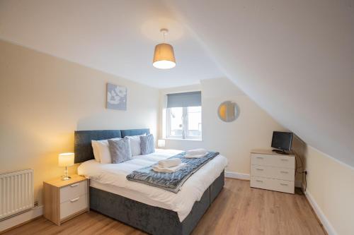 a bedroom with a large bed and a window at 2 Bedroom Penthouse, Clockhouse, Hoddessdon in Hoddesdon