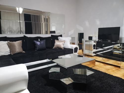 a living room with a black couch and a glass table at Apartments & Pool Villa White House in Pančevo