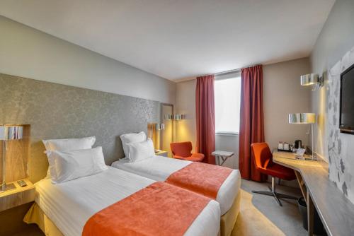 ヴェリジー・ヴィラクブレーにあるベスト ウェスタン プラス パリス ヴェリジーのベッドとデスクが備わるホテルルームです。