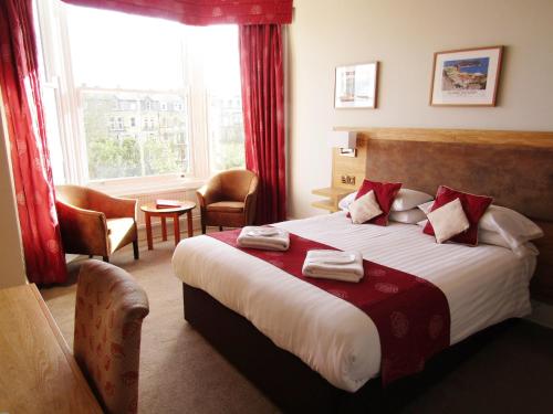 a hotel room with a large bed with red curtains at The Red Lea Hotel in Scarborough