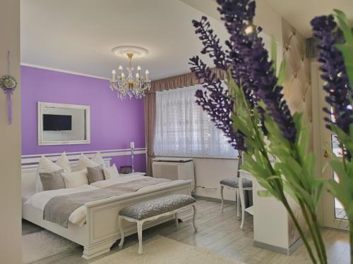 a bedroom with purple walls and a bed and a vase of flowers at Anna Panzió in Herend