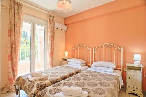 Duas camas num quarto com paredes cor-de-laranja e uma janela. em The Doctors House em Kassiopi